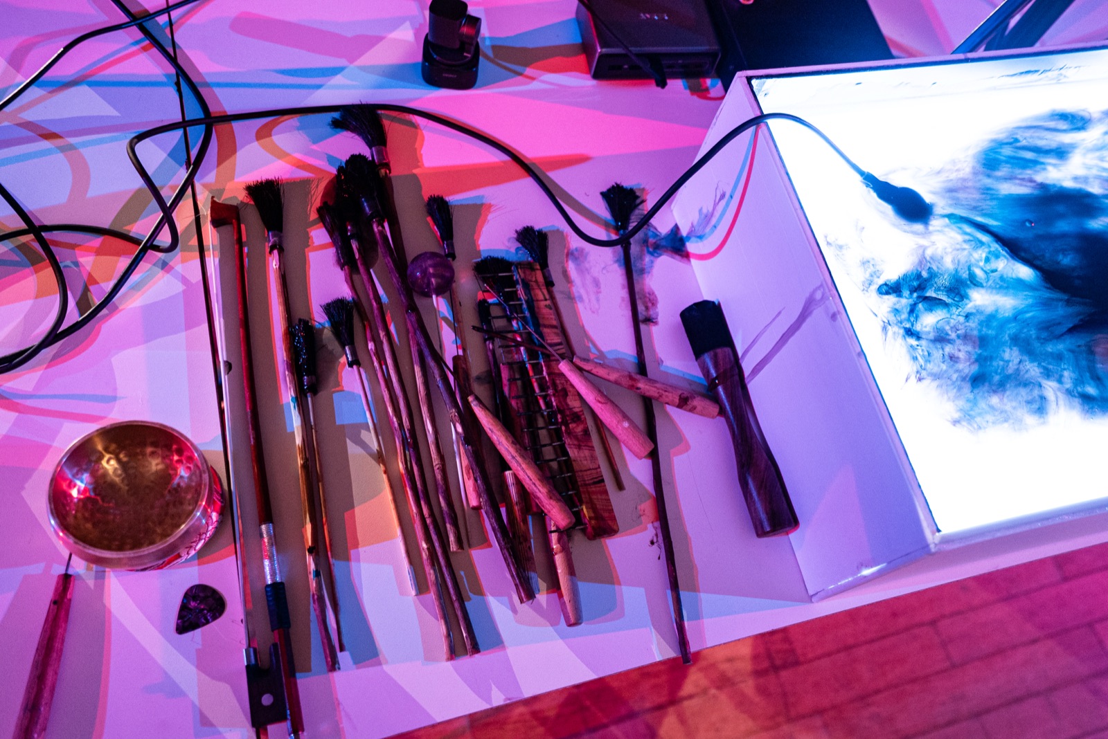 object table: brushes, styluses, bowed bowl, noise box beside the lit tray